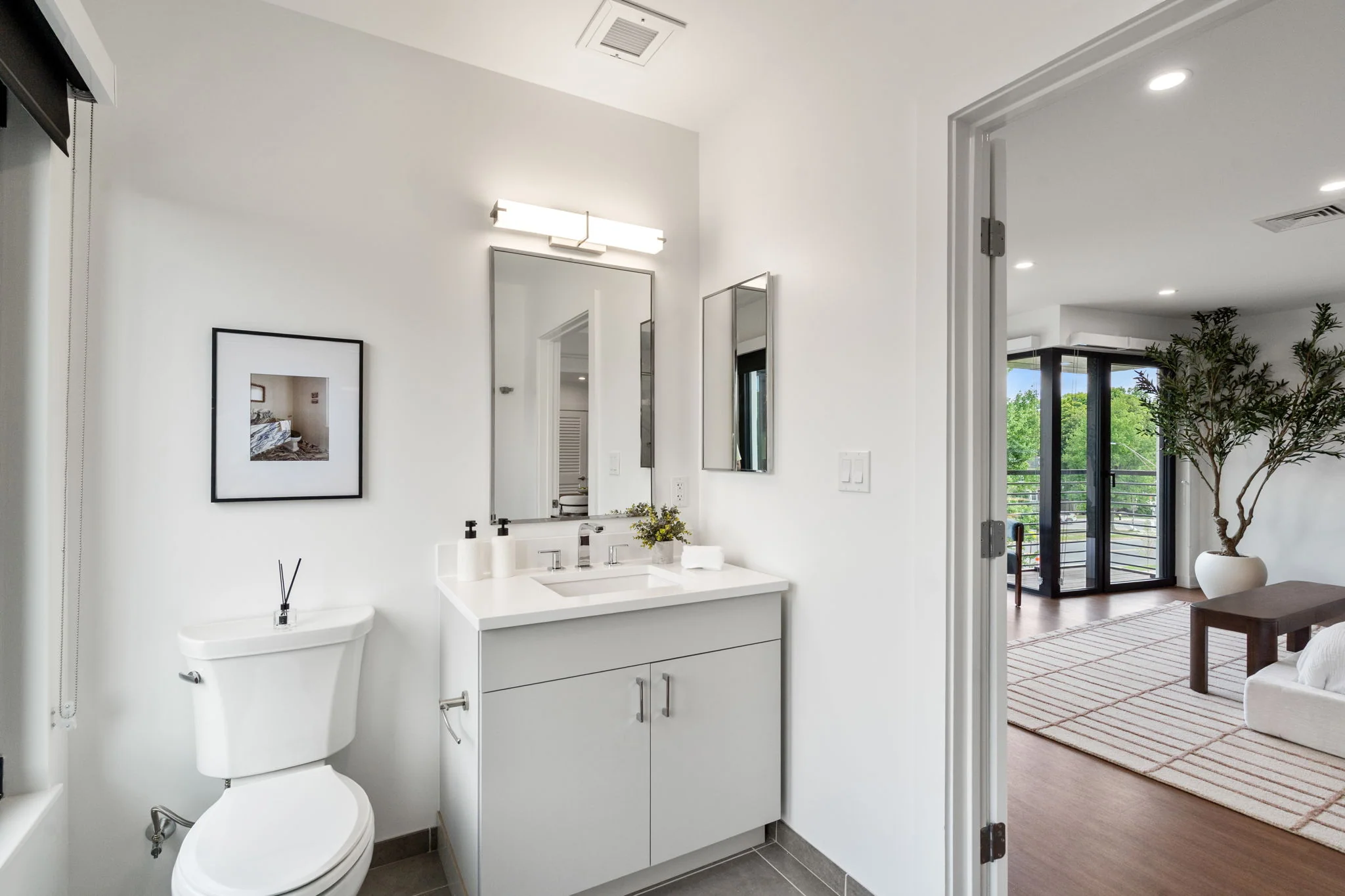 Bathroom vanity and toilet with the bedroom visible through the doorway
