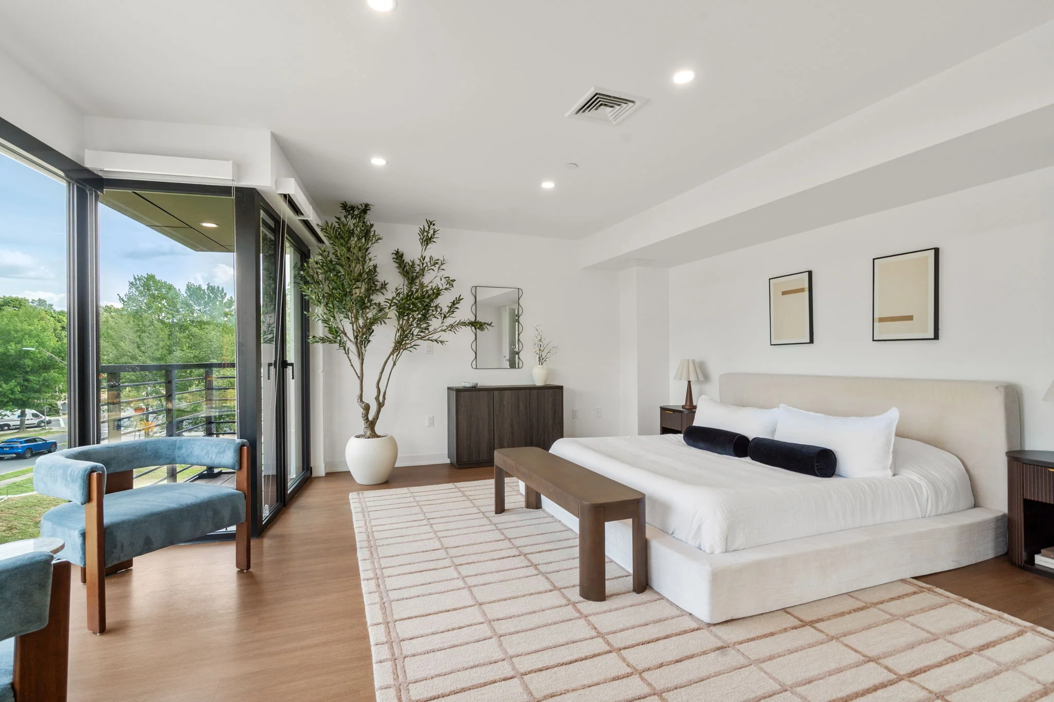 Bedroom with a white bed, blue armchairs, and balcony doors