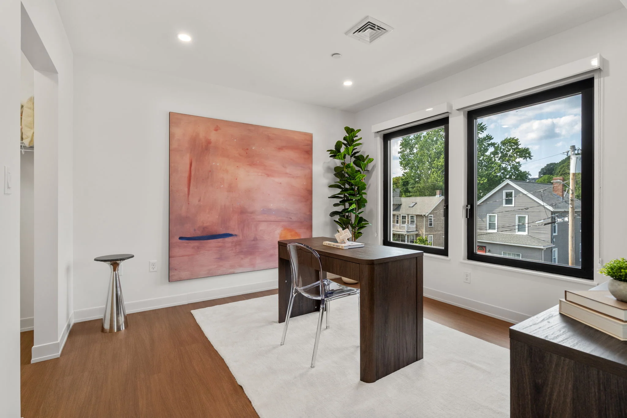 Wide view of the home office with a wooden desk and corner windows