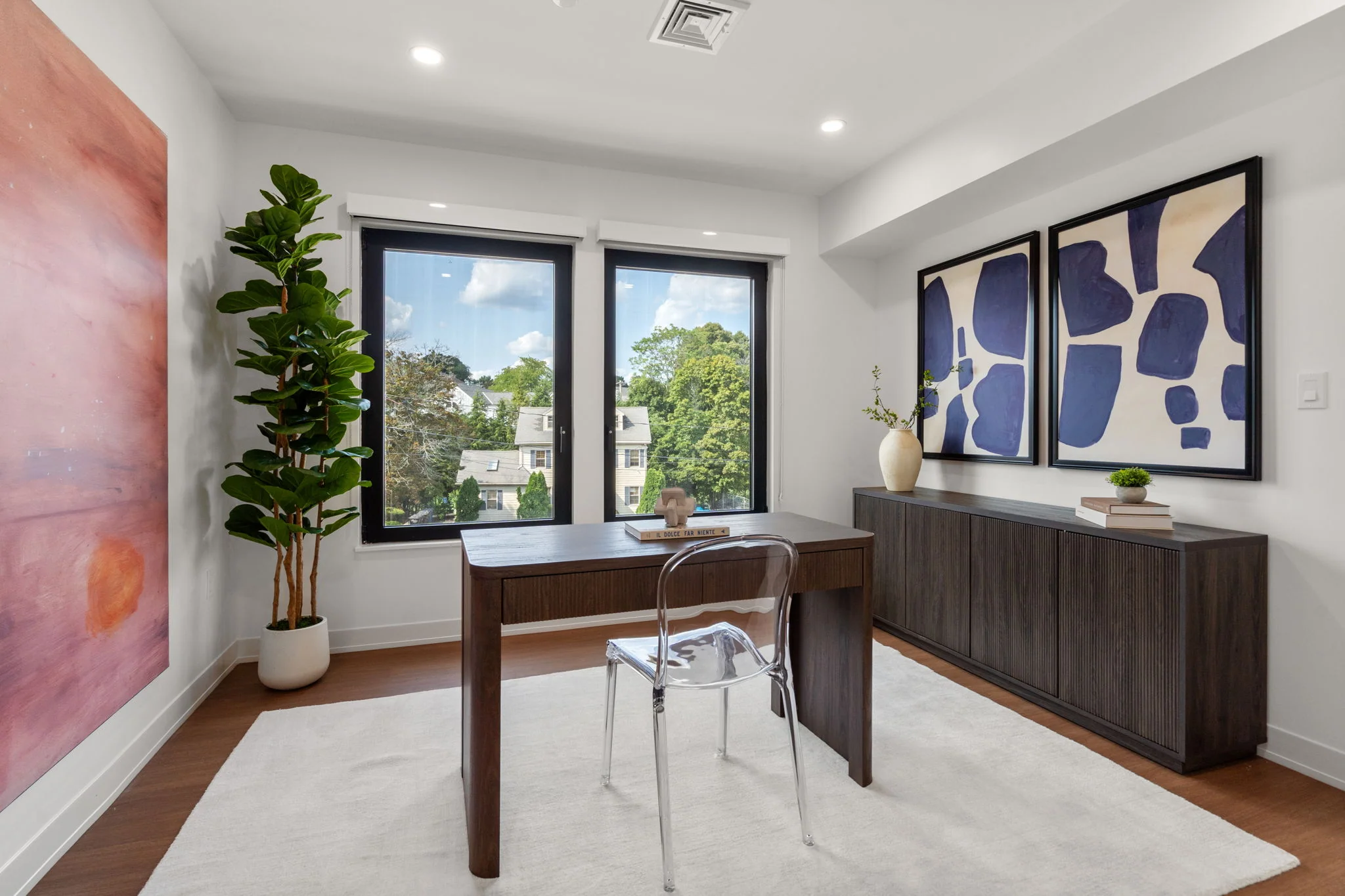 Home office with a wooden desk, window, and blue artwork