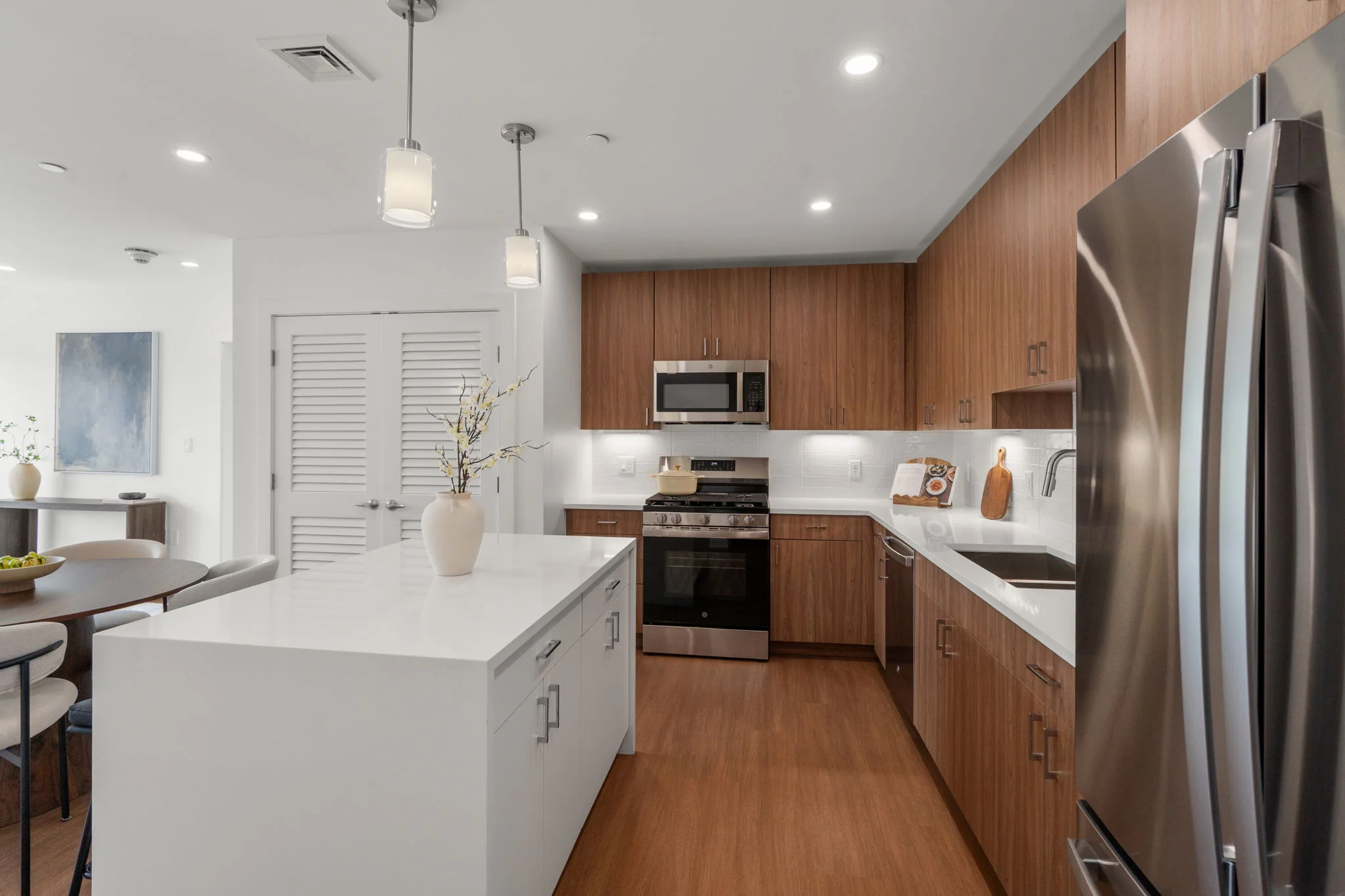 Kitchen island facing the range, microwave, and wood cabinetry