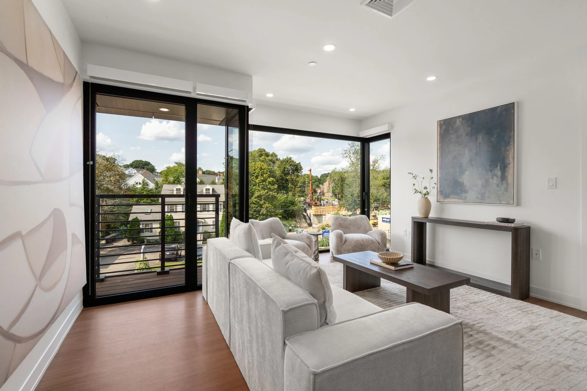 Living room with balcony doors and a console beneath abstract artwork